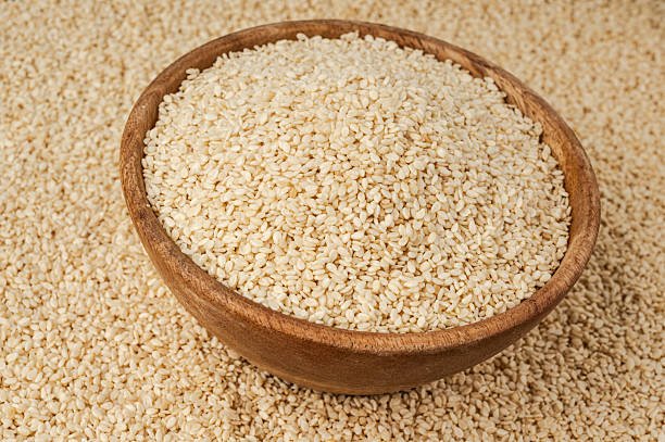 Sesame seeds in bowl closeup, white small benne grains. Sesamum indicum fruits texture