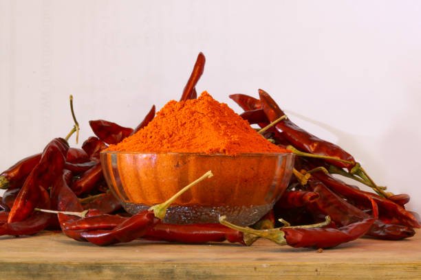 Red chillies with red chilly powder on white background.